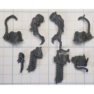 May include: A set of gray plastic miniature figures for a tabletop game. The figures are of a humanoid creature with a chainsaw and a claw.