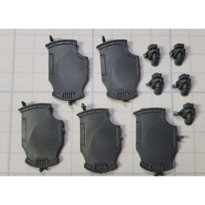 May include: A collection of unpainted, gray plastic miniature shields and weapon components. The shields have a curved, rectangular design with a decorative bottom and top. Several miniature weapon components are also included.
