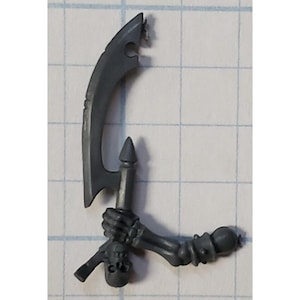 May include: A gray plastic miniature of a skeletal hand holding a curved blade weapon. The weapon has a pointed tip and a curved blade. The hand is holding the weapon in a gripping position.