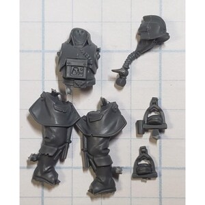 May include: A set of grey plastic miniature figures for a tabletop wargame. The figures are of a space marine in various poses, including a torso, legs, and a helmet with a breathing apparatus.