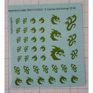 May include: A sheet of green and white waterslide decals featuring various dragon designs. The decals are labeled "Alpha Legion" and include the text "mponent code: 99510102021 © Games Workshop 2018".