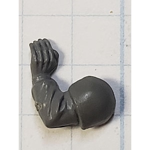 May include: A gray plastic miniature arm with a closed fist, designed for use in a tabletop wargame or role-playing game.