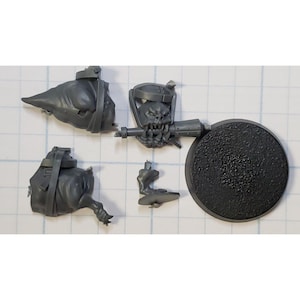 May include: A set of gray plastic miniature figures for a tabletop game. The set includes a head, body, legs, weapon, and a round base.