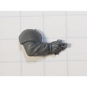May include: A gray plastic miniature arm with a hand holding a weapon. The arm is sculpted with detail and is ready to be painted.