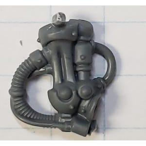 May include: A gray plastic miniature component featuring a central mechanical housing with a curved ribbed hose extending from the side. The piece includes circular details, cylindrical protrusions, and a small top connector on a grid background.