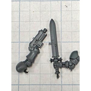 May include: Two unpainted gray plastic miniature arm components. One arm holds a blocky firearm with a short barrel, while the other arm features a hand gripping a long, straight sword with a skull-shaped crossguard detail.