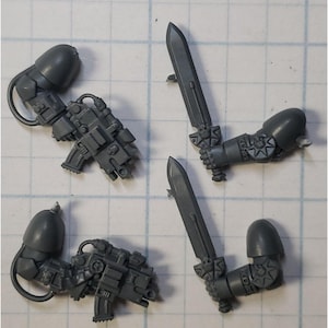 May include: Four gray plastic miniature figures with different weapons. The figures are holding a sword, a gun, and a pistol. The figures are for a tabletop game.