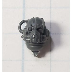 May include: A gray plastic miniature helmet with a detailed design, including a visor and a small antenna. The helmet is a part of a miniature wargaming set.
