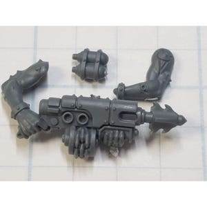 May include: A collection of gray plastic miniature weapon parts, including a gun with a spiked tip, two arms, and a pair of cylindrical canisters. The parts are designed for a miniature figure or model.