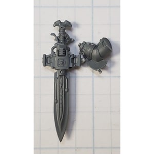 May include: A gray plastic model of a sword with a detailed handle and blade. The sword is in two pieces, with the handle and blade separate.