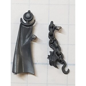 May include: Two gray plastic miniature figures for a tabletop game. One figure is a cape with a crescent moon symbol on top. The other figure is a chain with a bat-like creature at the end.