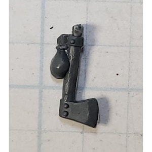 May include: A gray plastic miniature axe with a small pouch attached to the handle. The axe has a wooden handle and a metal blade.