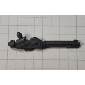 May include: A gray plastic sci-fi weapon with a barrel and a detailed handle. The weapon has a futuristic design with multiple grooves and a textured surface.