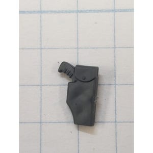 May include: A small, dark gray toy gun and holster set. The gun has a detailed handle and the holster features a flap with a button closure. The set is made of plastic and is designed for play.