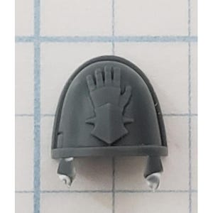May include: Gray plastic miniature shoulder pad with a raised design of a hand in a gauntlet. The hand is holding a sword.