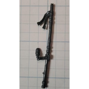 May include: A black plastic miniature weapon with a long handle and a small, round, detailed head. The weapon has a black fabric streamer attached to the top.