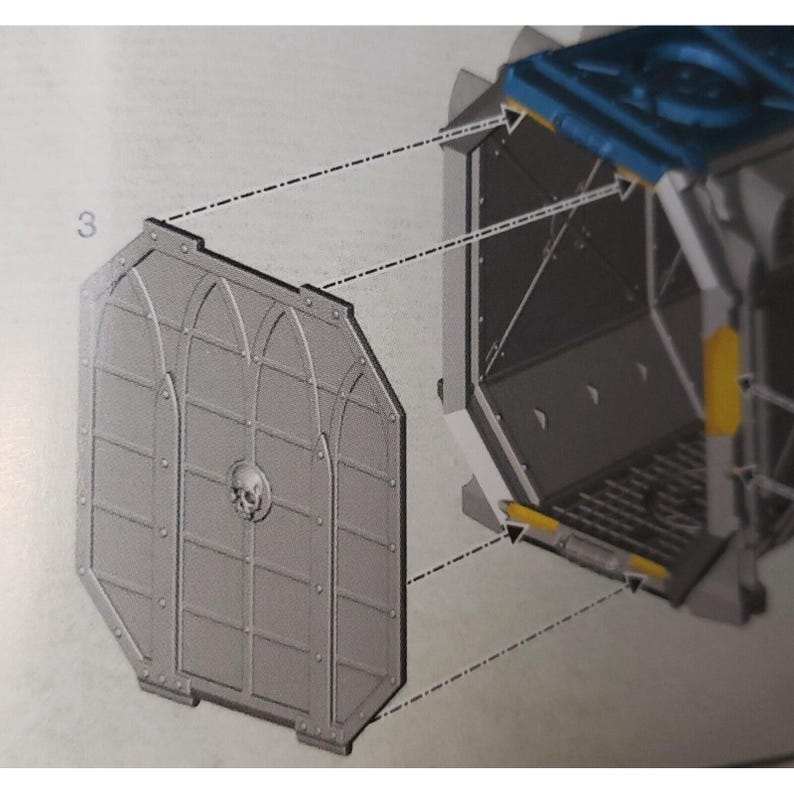 May include: A detailed diagram showing how to assemble a model kit. The diagram shows a gray metal door with a skull design and a blue and gray compartment with a yellow stripe.