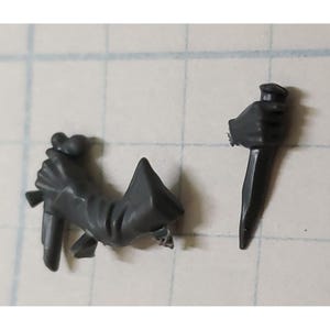 May include: Two gray plastic miniature figures of hands holding knives. The figures are for a tabletop game or role-playing game.