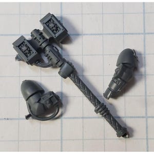 May include: A set of three gray plastic Warhammer 40k miniatures. The miniatures are of a power fist, a power claw, and a power sword.