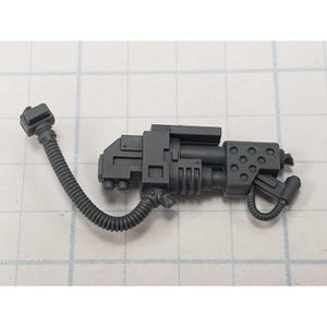 May include: A gray plastic miniature weapon with a ribbed hose and various geometric shapes. The weapon has a rectangular body with circular and rectangular details. The hose connects to a small rectangular piece. The weapon is designed for a miniature game.