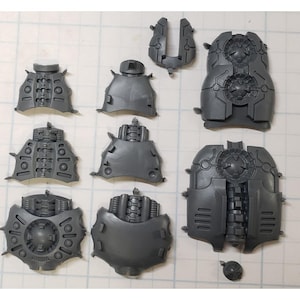 May include: A set of gray plastic model pieces for a robot or robot-like figure. The pieces are various shapes and sizes, and some have details like gears and pipes.