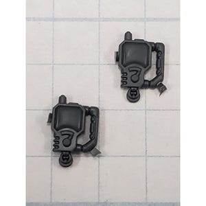 May include: Two dark gray plastic miniature components. Each component has a rectangular body with a circular top, a handle, and a nozzle. The number "7" is visible on the front of each component.