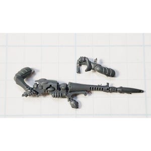 May include: Gray plastic model kit of a sci-fi weapon with a long barrel and a detailed design.