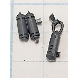 May include: Three small, dark gray plastic miniature components. Two are cylindrical canisters with ribbed detailing and small attachment points. The third component is a cylindrical piece with a loop at the top and a textured, ribbed surface.