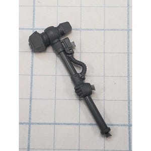 May include: A dark gray miniature hammer with a rectangular head and a detailed handle. The handle features a grip, a coiled tube, and various mechanical details. The hammer is likely a component of a larger model or game piece.