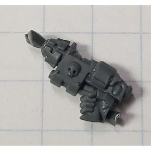 May include: A gray plastic miniature weapon with a skull design on the side. The weapon has a barrel, a handle, and a trigger.