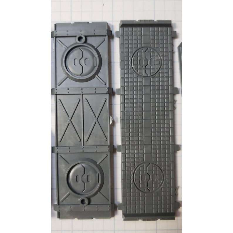 May include: Two gray plastic panels with a textured surface and a circular design. The panels are designed for a model kit.