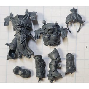 May include: A set of gray plastic miniature figures for a tabletop game. The figures are in various poses and include a helmet, torso, legs, and arms.