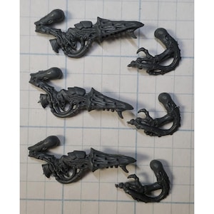 May include: Three sets of grey plastic miniature parts for a model kit. Each set includes a weapon and a claw.