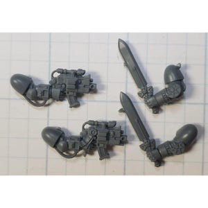 May include: Four grey plastic miniature figures for a tabletop game. Two figures hold swords, and two figures hold guns.