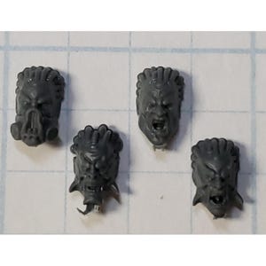 May include: Four gray plastic miniature heads with different facial expressions. The heads are detailed with sculpted hair and facial features.