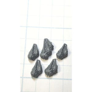 May include: Six gray plastic miniature heads with detailed facial features. The heads are designed for use in tabletop wargaming or model building.