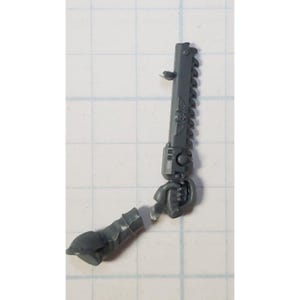 May include: A gray plastic model kit of a chain sword weapon for a miniature figure. The weapon is in two pieces, the handle and the blade.