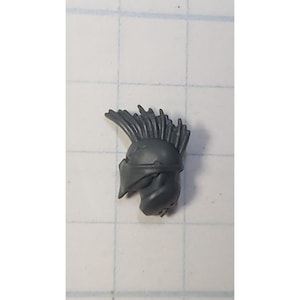 May include: A gray plastic helmet with a spiky crest. The helmet is designed for a miniature figure.