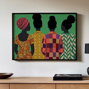 May include: A framed wall art print featuring four figures seen from behind against a solid green background. The figures have dark silhouettes and hairstyles including a headwrap and buns, wearing patterned tops in orange, yellow, and red.