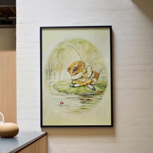 May include: Framed art print featuring a frog character in a white outfit, sitting on a lily pad. The frog is holding a leaf, with a pond and reeds in the background. The artwork has a vintage, storybook style.