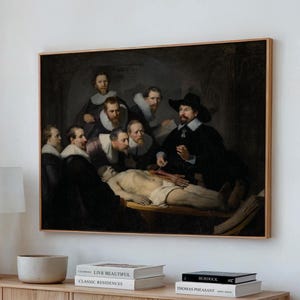 May include: A framed print of a historical painting depicting a medical demonstration. A man in a black hat performs a dissection on a body, surrounded by several men in dark attire. The artwork is displayed on a light-colored wall.