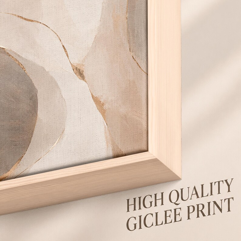 May include: A framed wall art piece featuring an abstract composition of soft beige, cream, and grey organic shapes with thin gold-colored lines. The artwork is encased in a light-toned wooden frame. The text HIGH QUALITY GICLEE PRINT is visible.