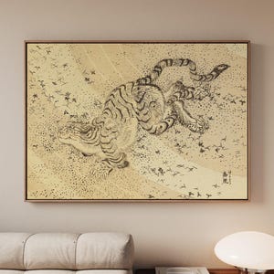 May include: A rectangular wall art print featuring a black ink illustration of a tiger on a textured beige background. The tiger is depicted in a dynamic pose with visible stripes, surrounded by small scattered leaf motifs and Japanese calligraphy.