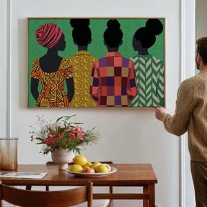 May include: A rectangular wall art print featuring four figures seen from behind against a solid green background. The figures wear patterned tops in orange, yellow, red, and green, with distinct hairstyles including a headwrap and buns.