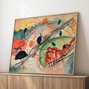 May include: Abstract watercolor painting in a wooden frame. The artwork features a vibrant mix of colors, including orange, green, blue, and yellow, with dynamic lines and shapes. The painting has a modern, expressive style.