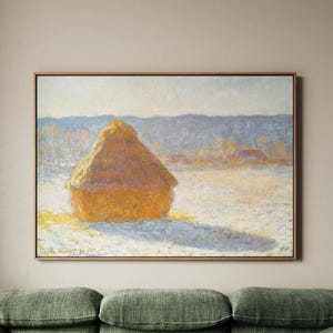 May include: A framed print of a landscape painting showing a golden haystack in a snowy field. The artwork, in a muted colour palette, depicts a winter scene with soft blues and yellows. The artist's signature is visible in the lower left corner.