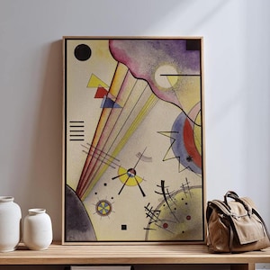 May include: Abstract art print in a wooden frame. The artwork features geometric shapes and lines in yellow, red, blue, and black against a cream background. A black circle and a purple cloud-like shape are also present. The art is displayed on a wooden shelf.