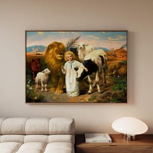 May include: A framed painting depicts a young person in a white robe holding a palm branch, surrounded by a lion, lamb, cow, and other animals. The artwork has a vintage style with a pastoral scene, featuring a blue sky and rolling hills.