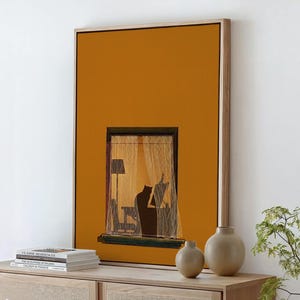 May include: A framed art print featuring a window scene with sheer curtains, a lamp, and a silhouette of a person. The artwork is set against a mustard-yellow background. Two beige vases and a stack of books are on a wooden surface.
