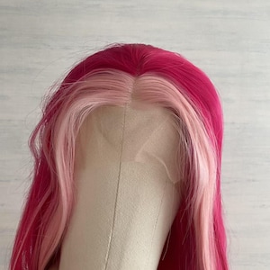 Pode incluir: Uma peruca rosa vibrante e rosa claro com cabelo longo e ondulado. A peruca apresenta uma coroa rosa escuro e uma se&ccedil;&atilde;o frontal rosa claro. A peruca &eacute; estilizada em uma cabe&ccedil;a de manequim, mostrando a cor e o estilo.